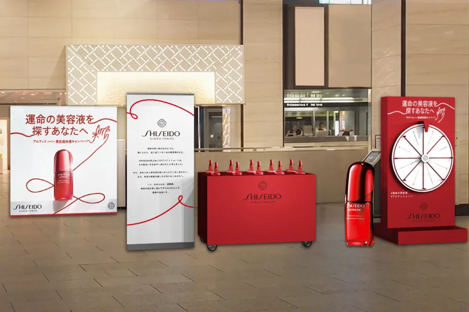 SHISEIDO（資生堂）アルティミューンのサンプリングイベント会場のイメージ。赤を基調としたカウンターにボトルが並び、その横にWチャンスで使用するルーレットが設置されている様子。